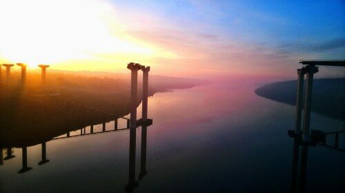 Солнышко встает над островом Хортица, новыми недостроенными мостами и Днепром. 